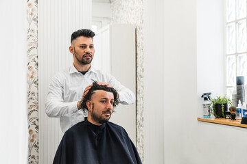 Hairdresser carefully applying hair replacement system on client's head, offering non surgical...