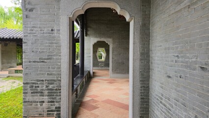A corridor of repeating arched doorways leading to a hexagonal window in traditional East Asian...