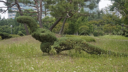 A playful topiary pine shaped like a dinosaur adds imagination and charm to the peaceful greenery...