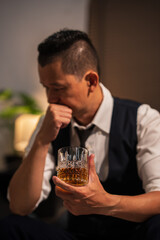Businessman holding a glass of whiskey and drinking on a sofa.