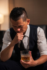 Businessman holding a glass of whiskey, sitting and drinking	