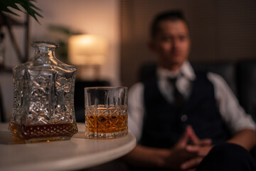 Businessman holding a glass of whiskey and drinking on a sofa.