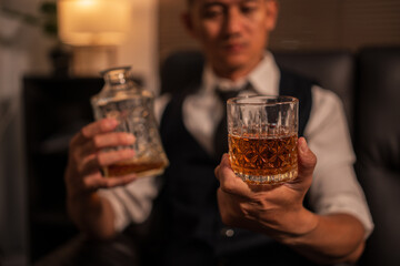 Businessman holding a glass of whiskey, sitting and drinking	