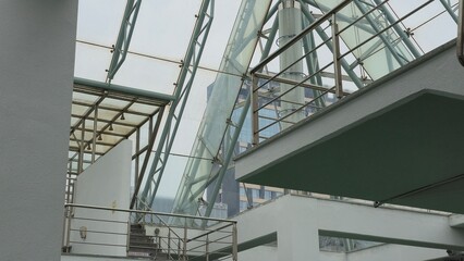 Modern architectural interior featuring layered platforms, steel railings, and a transparent glass ceiling.