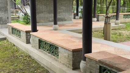A view of traditional stone benches with decorative lattice in a Chinese pavilion, surrounded by...