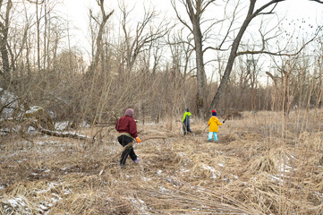 Families exploring nature in a winter landscape while cleaning up the overgrown area, fostering love for the outdoors and promoting community care for the environment