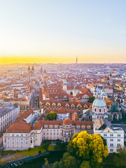 A breathtaking aerial perspective of Old Town Prague during sunrise showcases the vibrant rooftops...