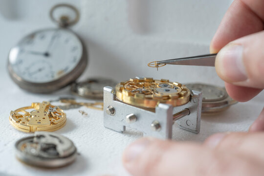 Close up of a professional watchmaker repairer working on an old vintage pocket watch in a workshop.