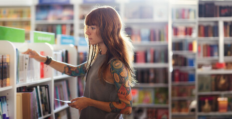 Web banner of shopping books. Side view of pretty Caucasian woman with tattoo choosing book in...