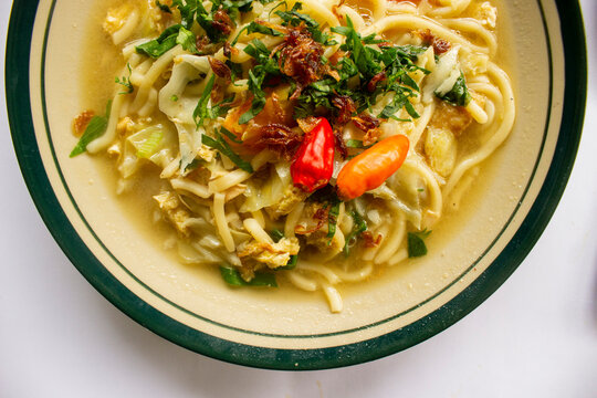 Mie godog Jawa or bakmi jawa or java noodle or Mie rebus or boiled noodles with spoon and fork. Indonesian traditional street food noodles from java, indonesia on white backgroud