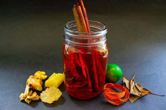 wedang uwuh is traditional herbal drink from indonesia. made from cinnamon, nutmeg and cloves leaves. Another ingredient is wood from the secang tree, ginger and lump sugar on black background