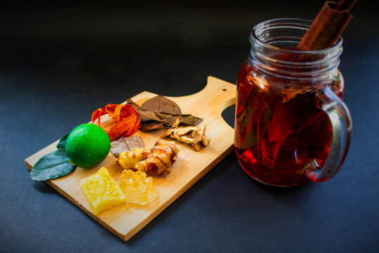wedang uwuh is traditional herbal drink from indonesia. made from cinnamon, nutmeg and cloves leaves. Another ingredient is wood from the secang tree, ginger and lump sugar on black background