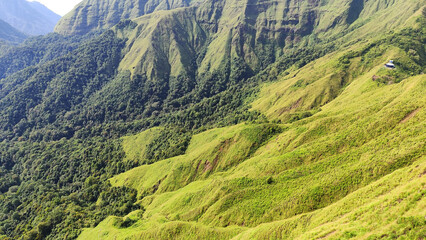 Summer mountain landscape with green grass and panoramic views of hills, trees, and sky
