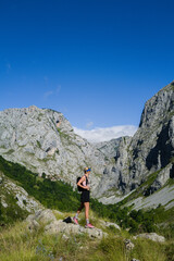 Fototapeta premium Woman standing with a backpack overlooking mountains
