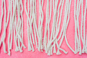 Rows of white macrame cords on pink background