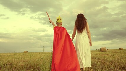 happy family. boy son with mother plays red cape superhero meadow. happy family concept. chidhood...