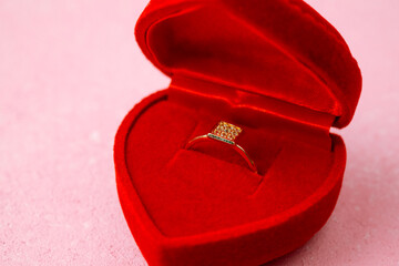 Square diamond ring in red heart jewelry box on pink background