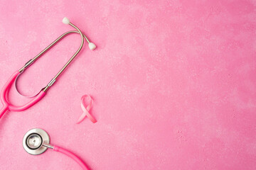 Pink stethoscope and breast cancer awareness ribbon on soft red background
