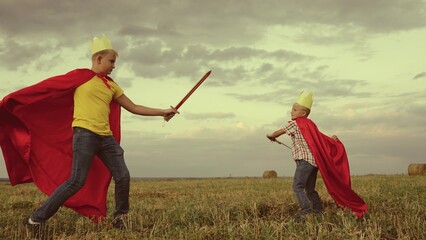 children superheroes play with swords field kings knights. dream childhood. little kid and his...
