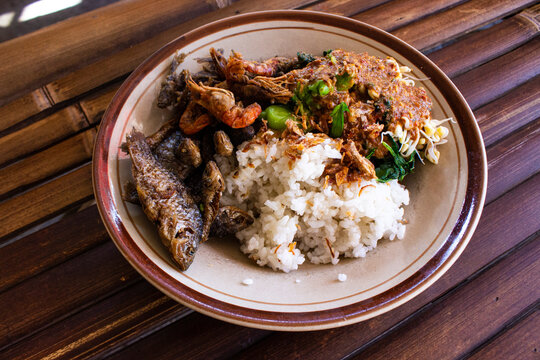 Nasi Pecel or sego pecel is Traditional Javanese rice dish of steamed rice with vegetable salad, peanut sauce, tempeh, tofu bean sprouts and crackers or peyek kacang. on black backgroud