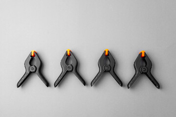 Row of black plastic clamps with orange tips on gray background