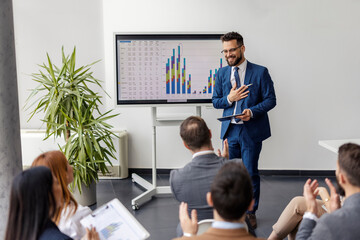 Presenter standing in front of attendees who are clapping at him on seminar.