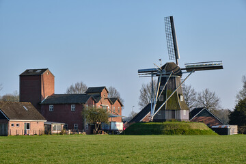Traditional Dutch grain windmill on a grassy mound in rural Achterhoek village