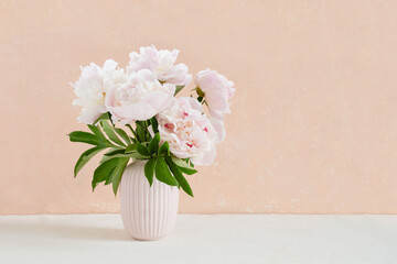 Bouquet of white peonies in vase on pastel vintage pink background. Bright interior. Cottagecore Aesthetics. Floral composition. Greeting card. International Womens Day