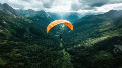 This breathtaking aerial shot captures a paraglider soaring through the dramatic mountain landscape, showcasing the beauty and thrill of adventure sports in nature.