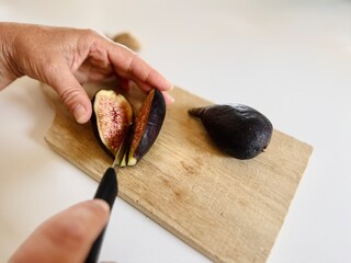 Early fig (breva) being cut on wooden table.