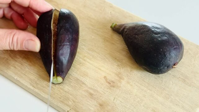Early fig (breva) being cut on wooden table.