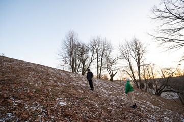Exploring the serene winter landscape at dusk, two figures navigate a snow dusted hillside under the fading light of day