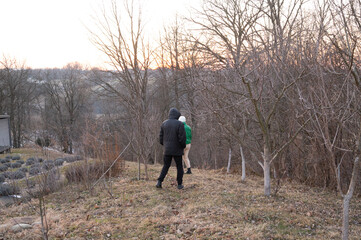 Strolling through a winter landscape at dusk near a hillside orchard with two figures exploring nature's beauty