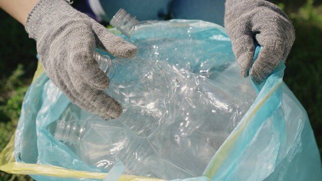 hand puts a plastic bottle in a bag, garbage for processing, eco, keep the environment clean, green planet safe, nature forest ecosystem, environmental protection problem, charitable activities.