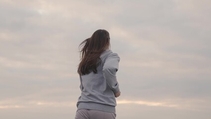 girl in sportswear runs against the sky at sunset, womens long-distance jogging, healthy lifestyle,...
