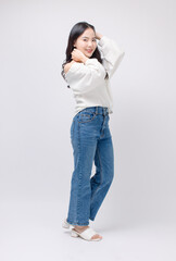 Full body portrait happy smile young asian beautiful woman curly hair wearing long sleeved shirt, blue jeans outfit, casual standing pose on white background joy positivity fashion lifestyle concept.