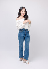 Full body portrait happy smile young asian beautiful woman curly hair wearing long sleeved shirt, blue jeans outfit, casual standing pose on white background joy positivity fashion lifestyle concept.