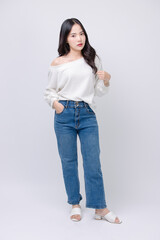 Full body portrait happy smile young asian beautiful woman curly hair wearing long sleeved shirt, blue jeans outfit, casual standing pose on white background joy positivity fashion lifestyle concept.