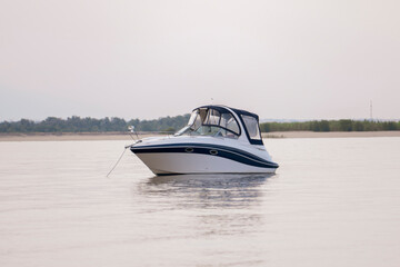 Motor boat anchored near sandy beach at calm waters during late afternoon