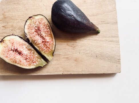 Fresh breba fig pieces on wooden board.