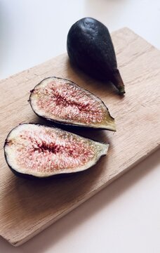 Fresh breba fig pieces on wooden board.