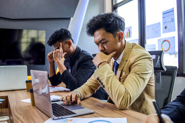 Worried Businessmen Sitting at Conference Table and Working on Laptop Having a Corporate Problem