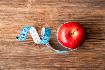 isolated red apple wrapped with tape measuring on white background. Diet and healthy living concept.