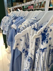 Blue and white patterned shirts hanging on a rack, featuring floral and checkered designs
