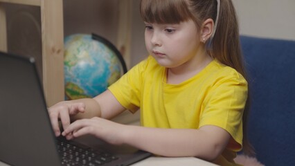 girl student presses keys laptop keyboard. childhood training. child kid doing homework desk...