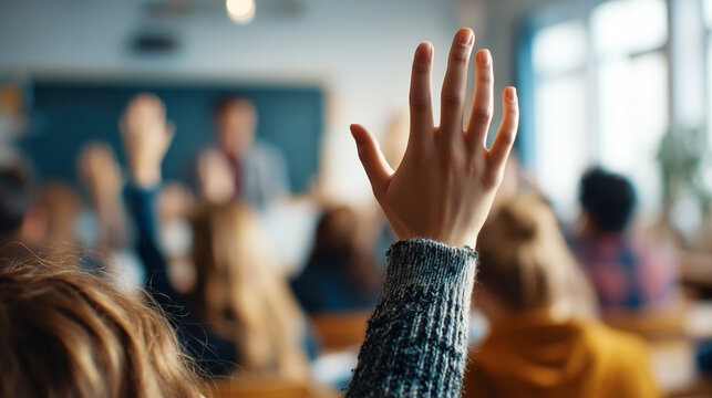 Student raising hand in classroom during lesson, close-up of hands on school desk, blurred background, back-to-school concept, education, participation, realistic cinematic photo