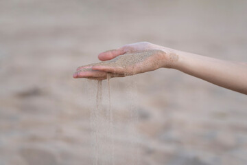 Fingers gracefully pouring sand on a beach, capturing fleeting moments of time