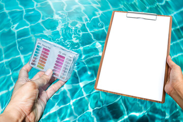 Water testing test kit in dipping in clear swimming pool water with blank report paper on wooden...