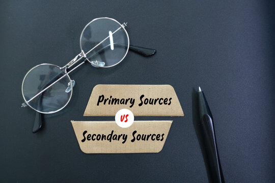 magnifying glass, pen and paper with the words Primary Sources vs Secondary Sources.