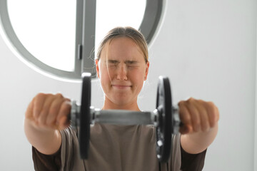 Young Gen Z woman doing barbell workout at home. Concept of mindful fitness, wellness, self-care,...